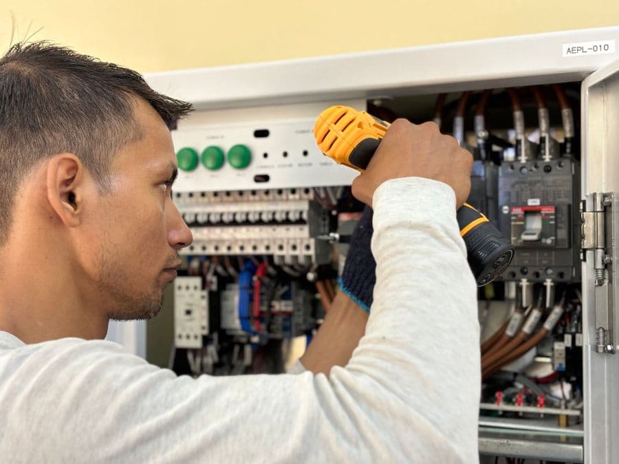 An electrician working on a home circuit-breaker panel