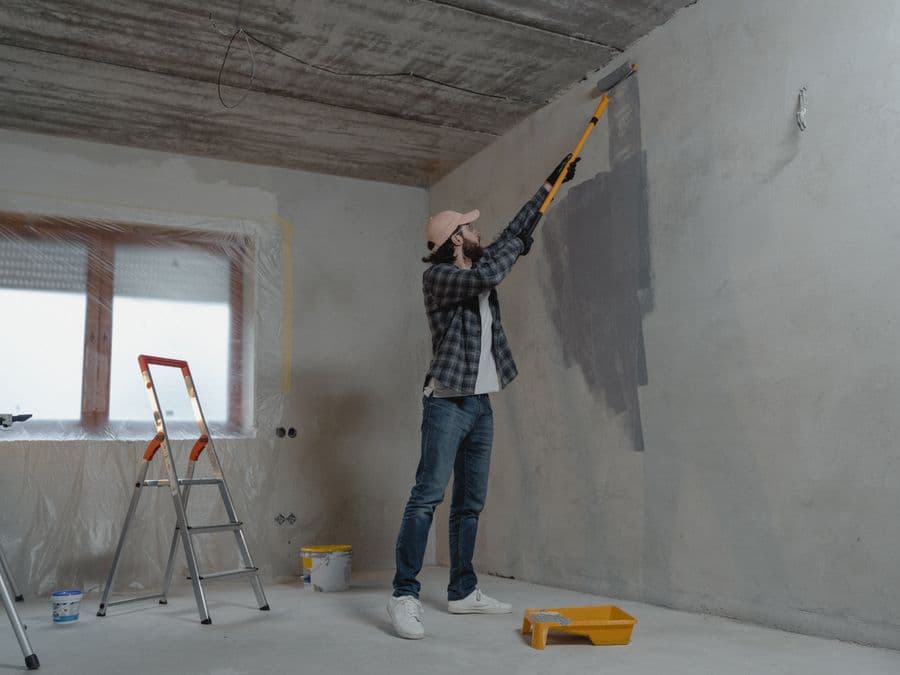 A professional painter rolling fresh paint onto a wall