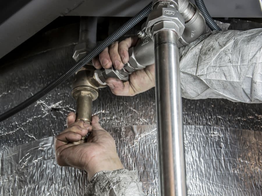 A plumber fitting copper pipe under a sink
